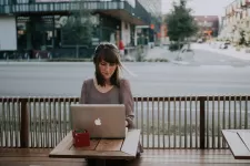 A person sitting with a laptop at a street crossing 