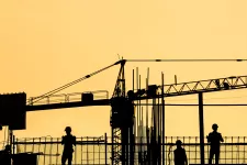 Photo showing a silhouette of a construction site with people working.