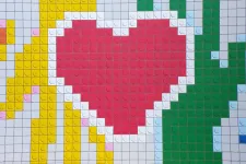 Foto som visar färgglada legobitar som bildar ett rött hjärta och två händer som möts.